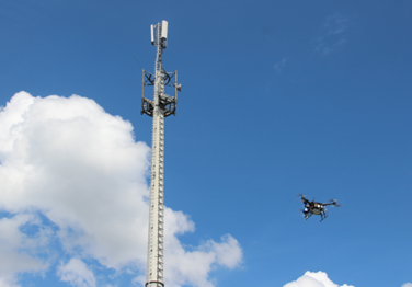 Drone-Based Antenna Measurement Drone flying near a tall antenna mast to measure RF signal radiation for installation accuracy and interference detection